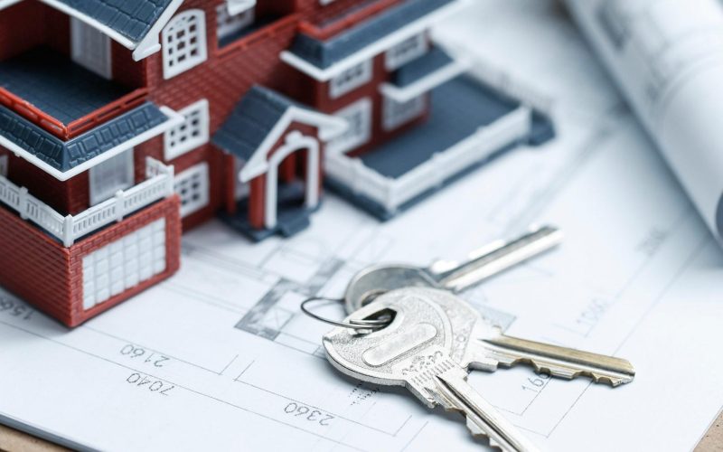 Villa house model, key and drawing on retro desktop (real estate sale concept)