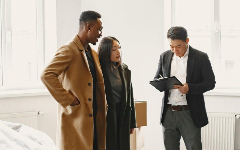 Young Couple Buying A New House. Asian woman and African man. Signing documents at new home.